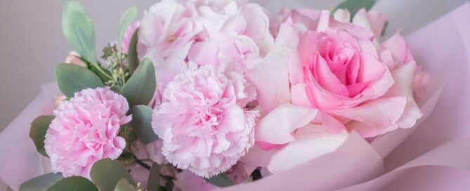 Soft pink floral bouquet with roses and carnations wrapped in pastel paper