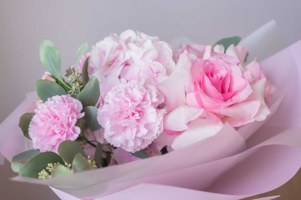 Soft pink floral bouquet with roses and carnations wrapped in pastel paper